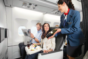 Passengers relax in leather seats in Air Transat Club Class as flight attendant offers a bottle of wine